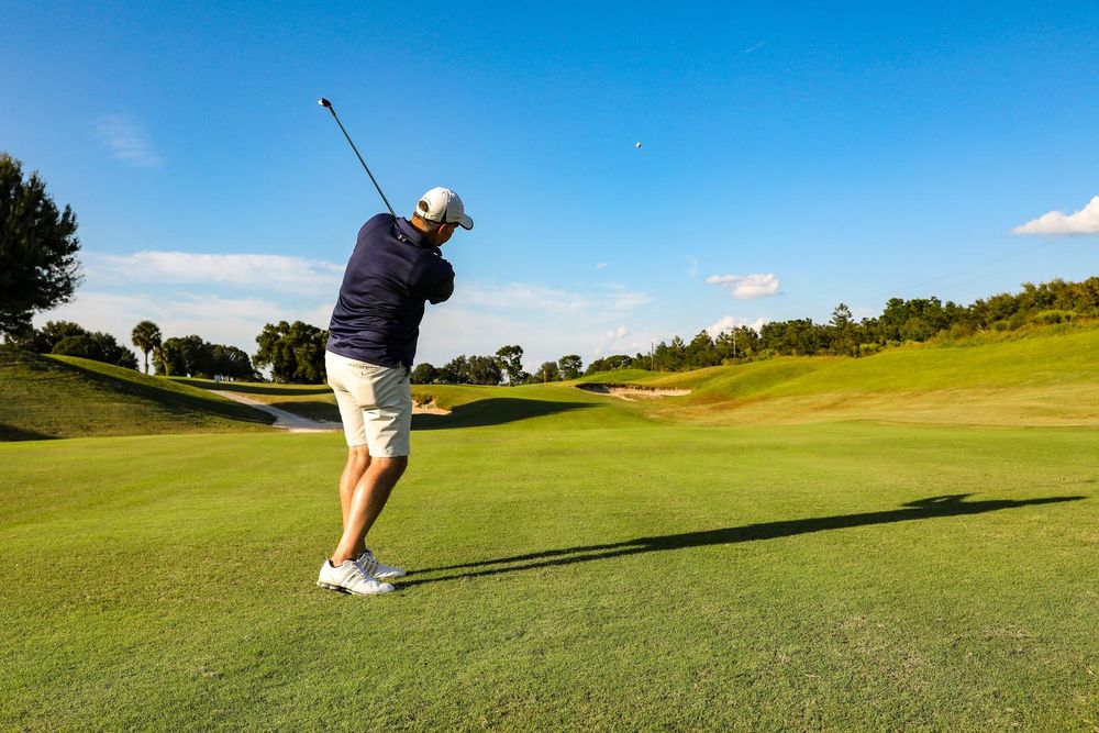 Golfer following through on an iron shot on a sunny golf course fairway