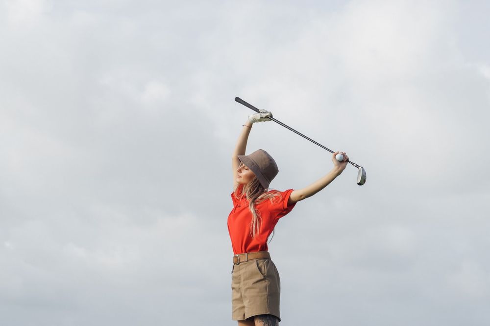 Golfer stretching overhead with a golf club to loosen her shoulders and upper back